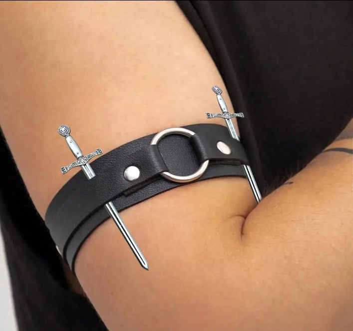 Adjustable leather arm band with decorative sword accents shown worn on arm