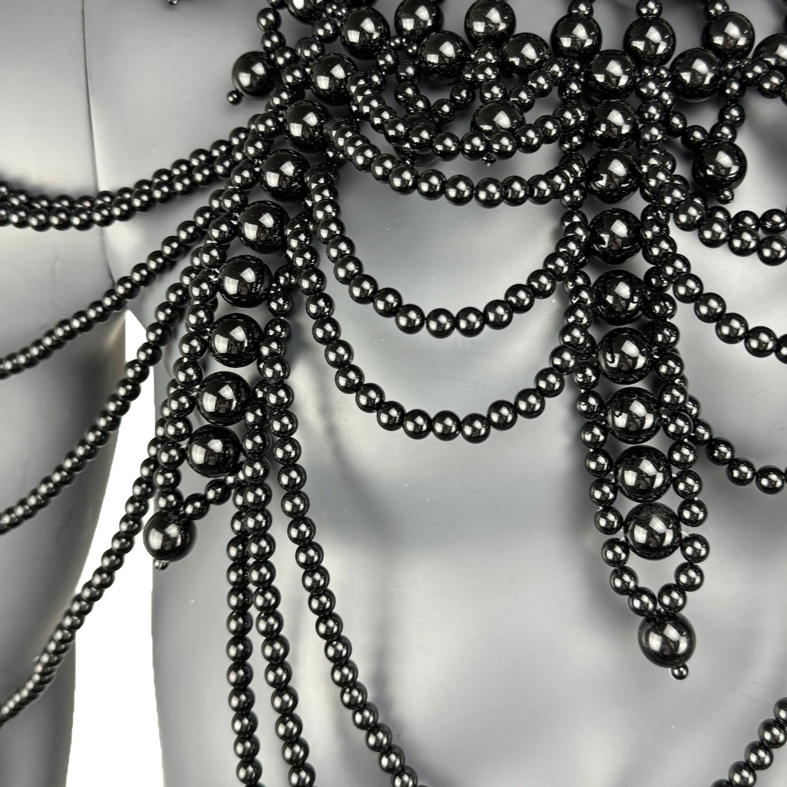 Close-up detail of black pearl strand construction on cape top chest