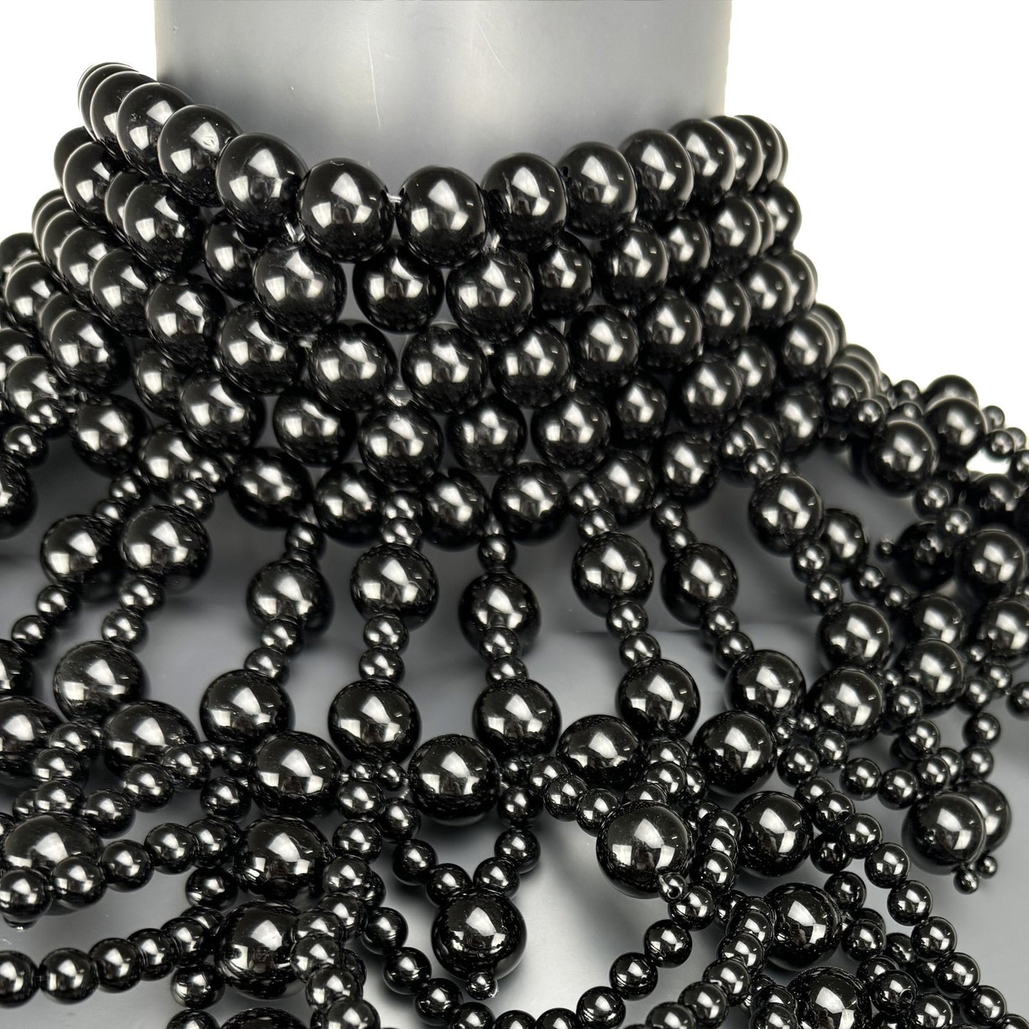 Close-up detail of black pearl strand construction on cape top front
