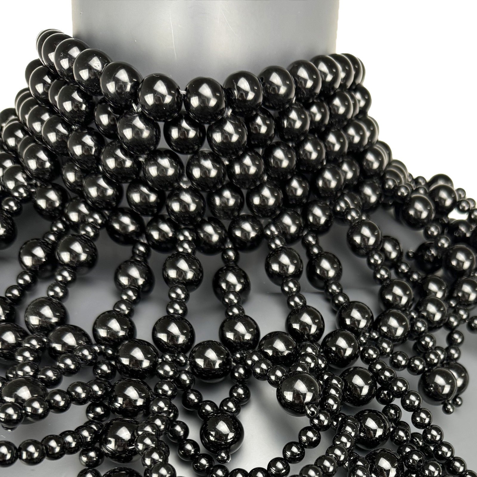 Close-up detail of black pearl strand construction on cape top front