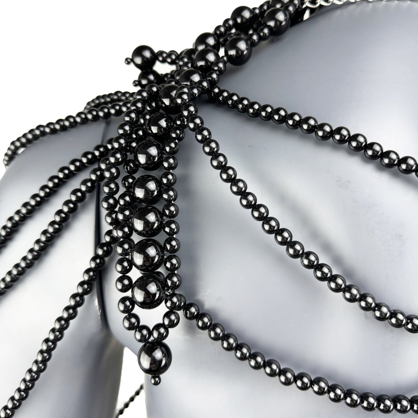Close-up detail of black pearl strand construction on cape top shoulder