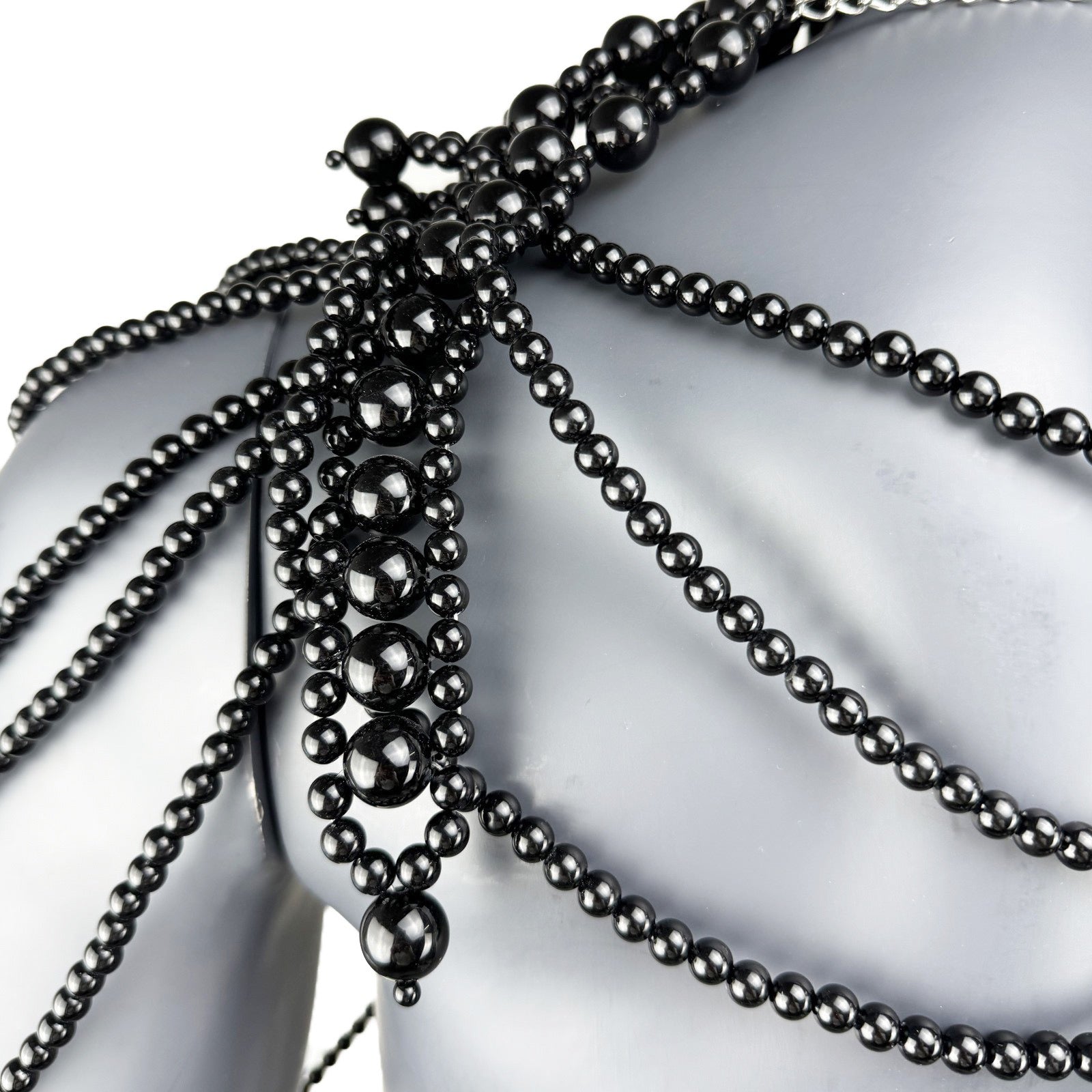 Close-up detail of black pearl strand construction on cape top shoulder