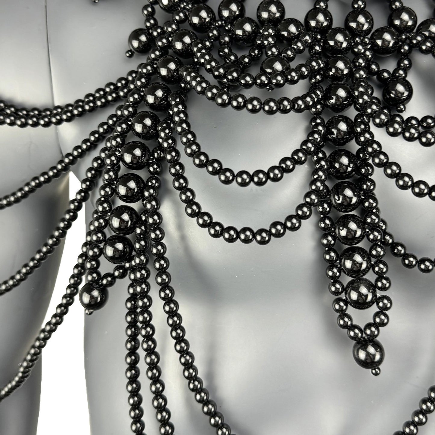 Close-up detail of black pearl strand construction on cape top