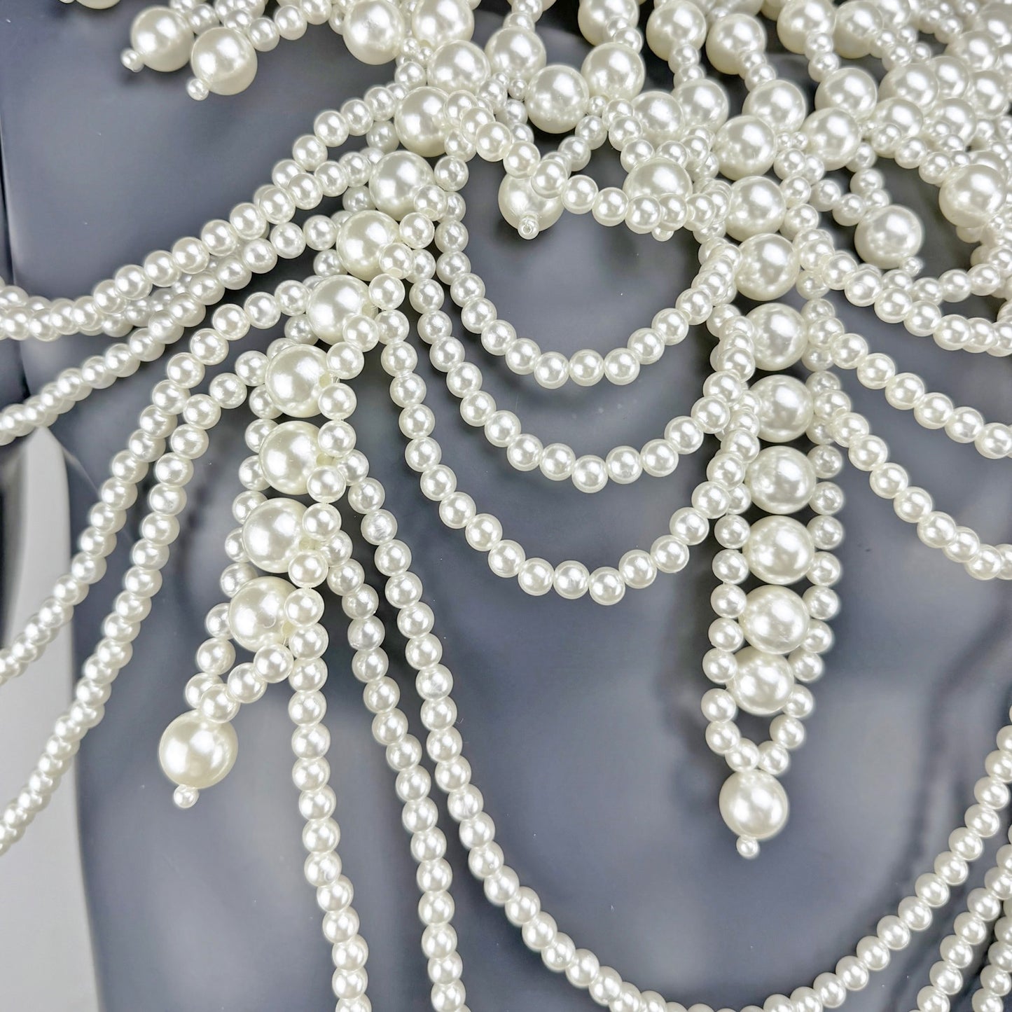 Close-up detail of layered white pearl strands on cape chest