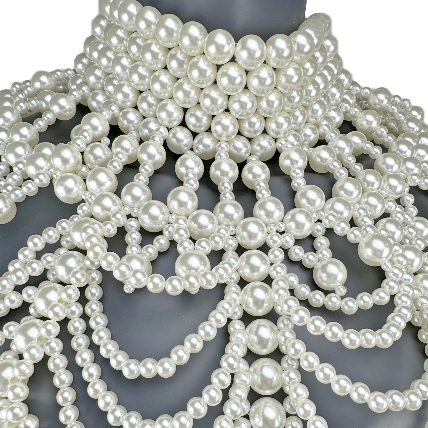 Close-up detail of layered white pearl strands on cape top neck