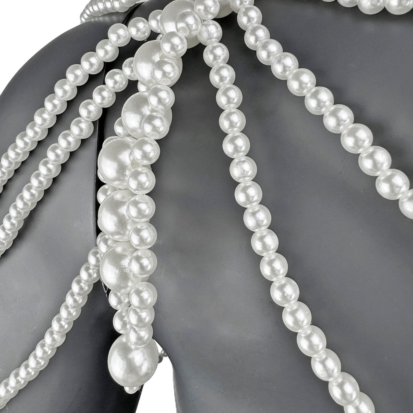 Close-up detail of layered white pearl strands on cape top shoulder