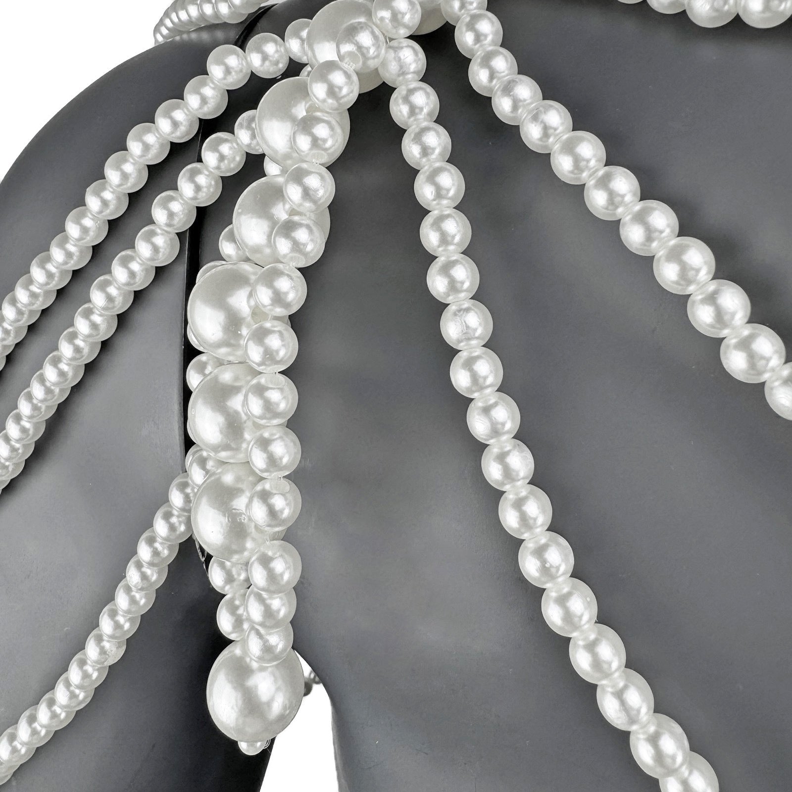 Close-up detail of layered white pearl strands on cape top shoulder