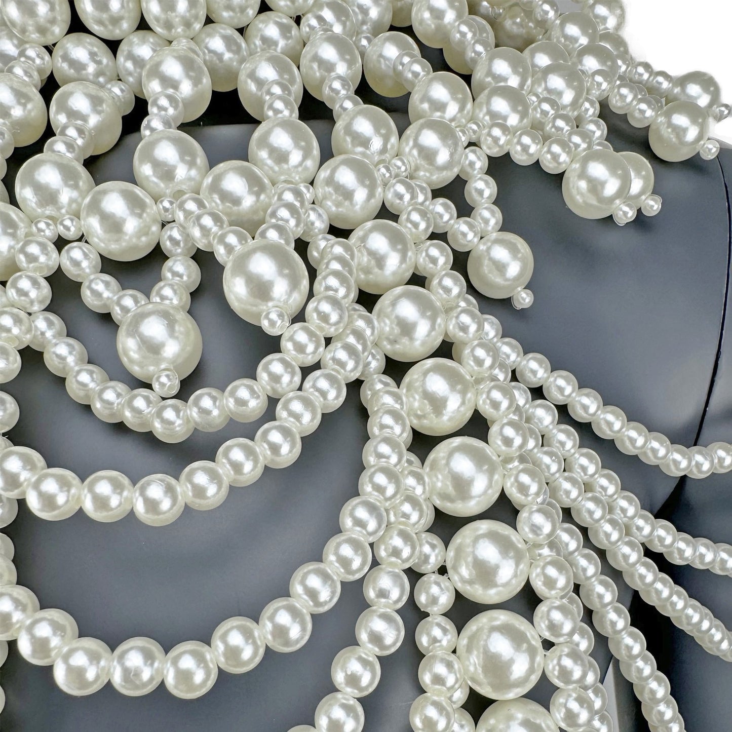 Close-up detail of layered white pearl strands on cape top