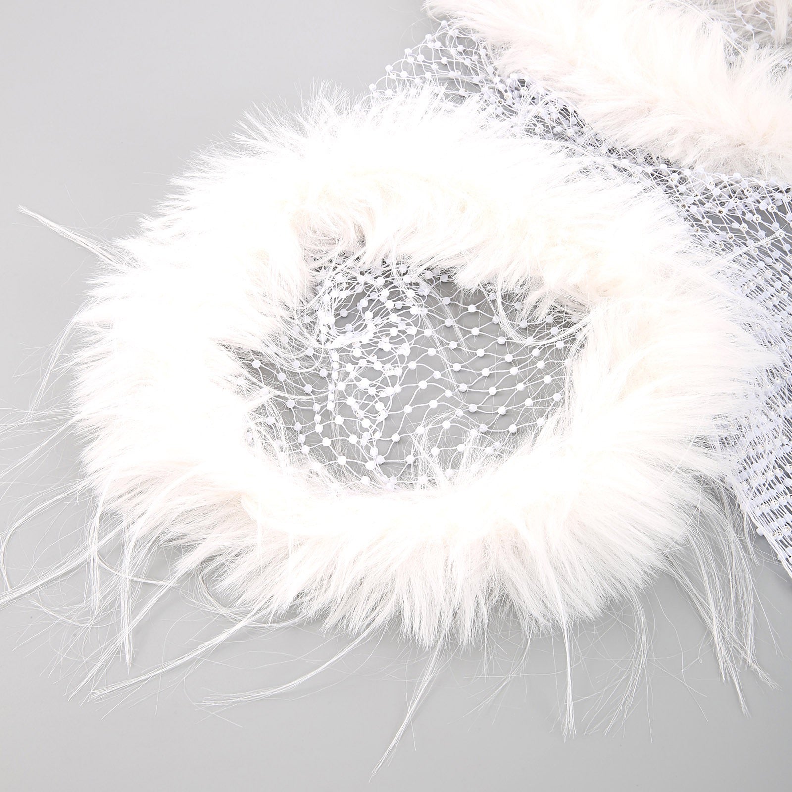 Close-up detail of feather shoulder trim on white rhinestone fishnet tank top